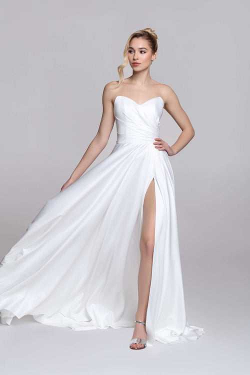 Strapless wedding dress with draped top and slit on the skirt.