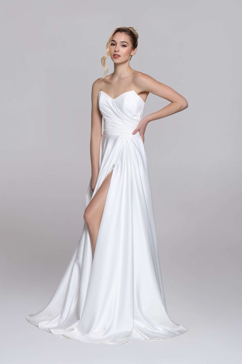 Strapless wedding dress with draped top and slit on the skirt.